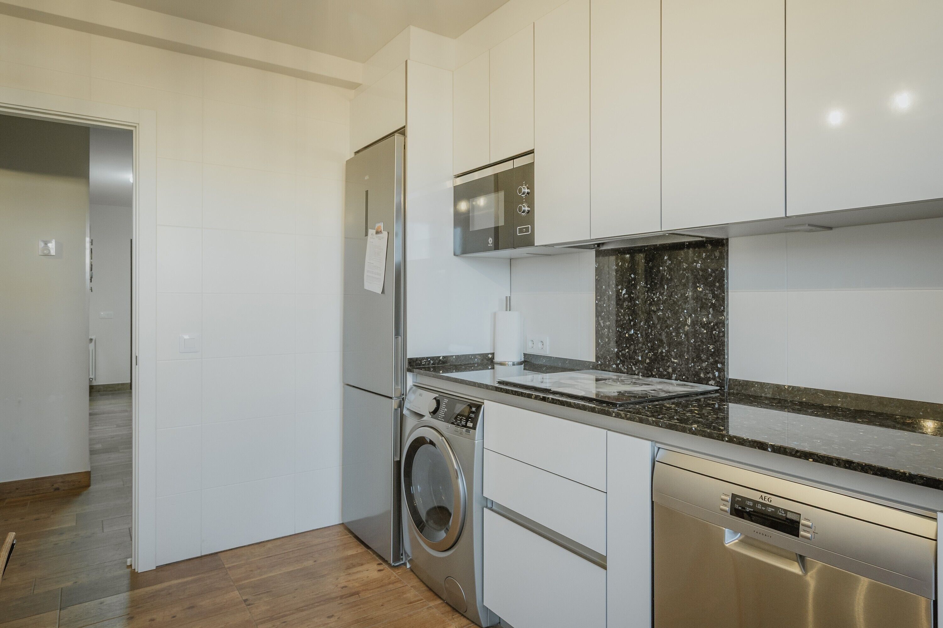 A modern kitchen with stainless steel appliances, white cabinetry, and a granite countertop.