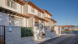 Une maison à deux étages avec une façade en briques, des poutres en bois et un ciel dégagé.