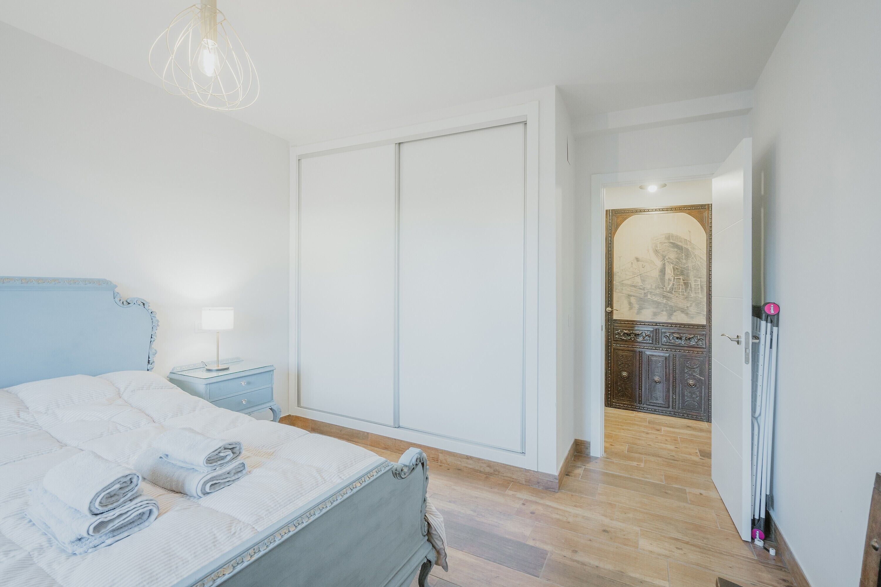 A bedroom with a bed, bedside table, and a wardrobe.