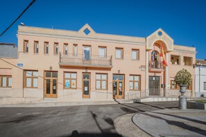 A two-story building with a central entrance, a balcony on the second floor, and a flagpole with flags. - Holiday Home 'Las Natillas Con V' with Mountain Views, Private Terrace and Wi-Fi (Martín Miguel)