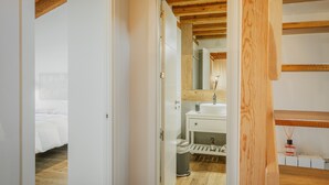 Une chambre à coucher avec un lit, une salle de bain avec un lavabo et un miroir, et un plafond en bois.