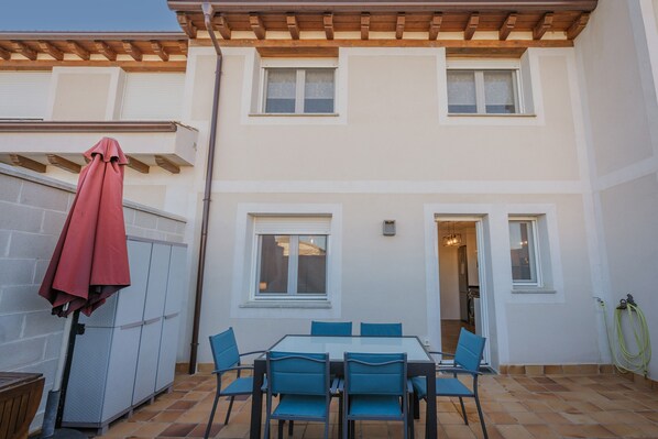 A patio with a table and chairs, a red umbrella, and a building with windows and a door. - Holiday Home 'Las Natillas Con V' with Mountain Views, Private Terrace and Wi-Fi (Martín Miguel)