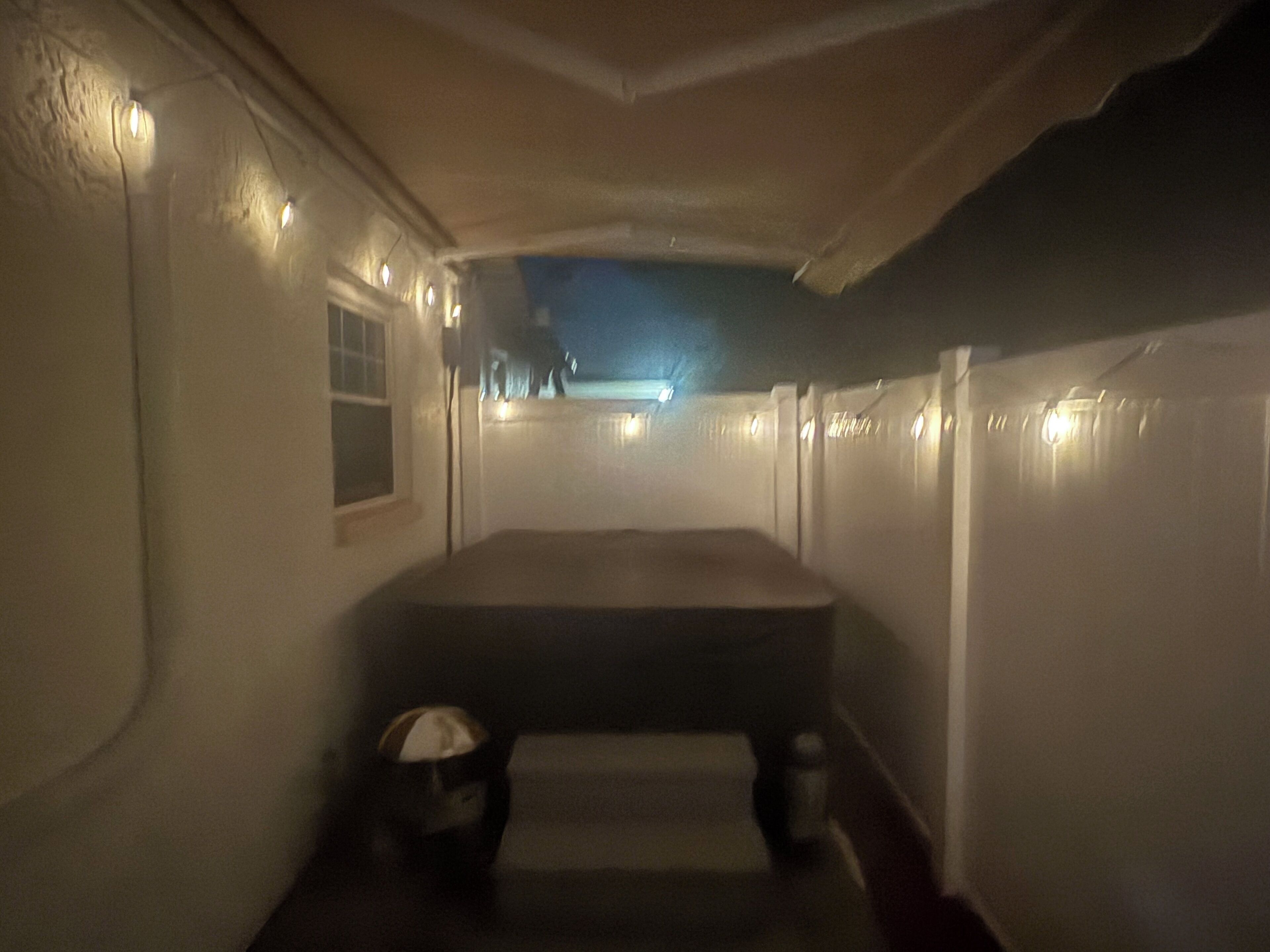 Un couloir étroit avec un banc, une petite table et une fenêtre sur le côté gauche.