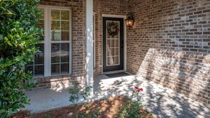 A brick house with a front door, a window, and a small garden area. - Beautiful 3 Bedroom On The River! (Vestavia Hills)