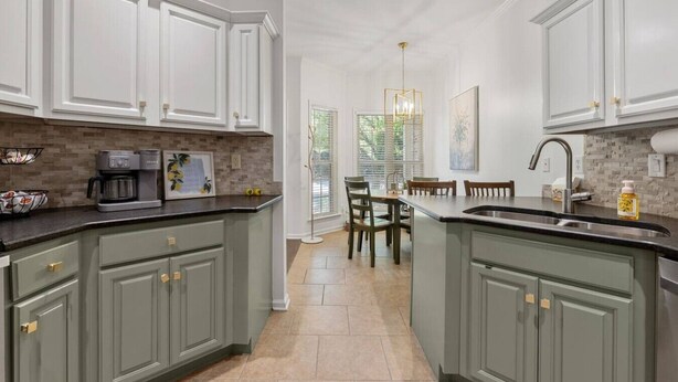 A kitchen with a central island, white cabinetry, and a coffee maker. - Beautiful 3 Bedroom On The River! (Vestavia Hills)