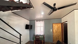 Un espacio habitable compacto con comedor, sofá, ventilador de techo y una escalera.