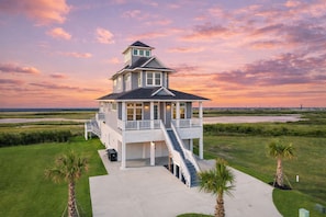 Une maison à deux étages avec un balcon, un escalier et une vue sur l’eau.