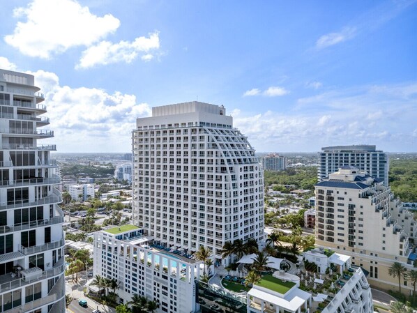 A high-rise hotel with multiple floors, a rooftop pool, and surrounding greenery.