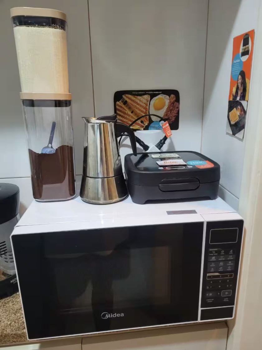 A microwave oven with a control panel, a coffee maker, and a kettle on a countertop.