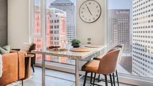 A modern kitchen with a large window, a clock, and a view of the cityscape. - Luxury Skyline View • Rooftop Pool, Sauna, Fire Pit • Steps to Stadiums & Dining (Cleveland)