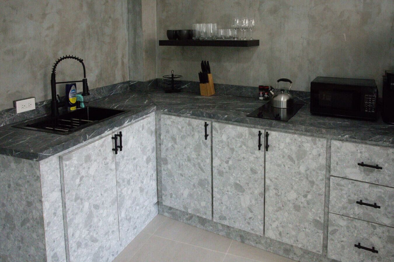 Eine Küche mit Granit Arbeitsplatten, einem Spülbecken, einem Wasserkocher, einer Mikrowelle und einem Messerblock.