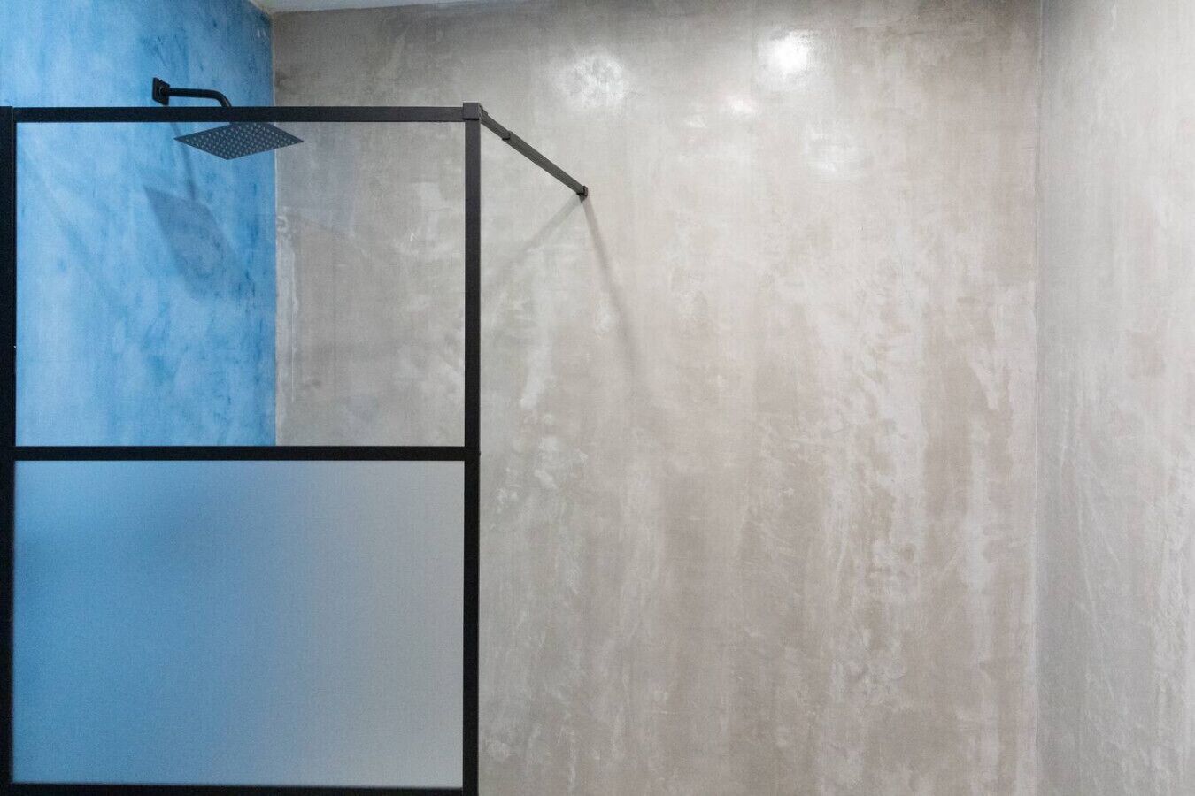 A shower enclosure with a black frame and a single showerhead.