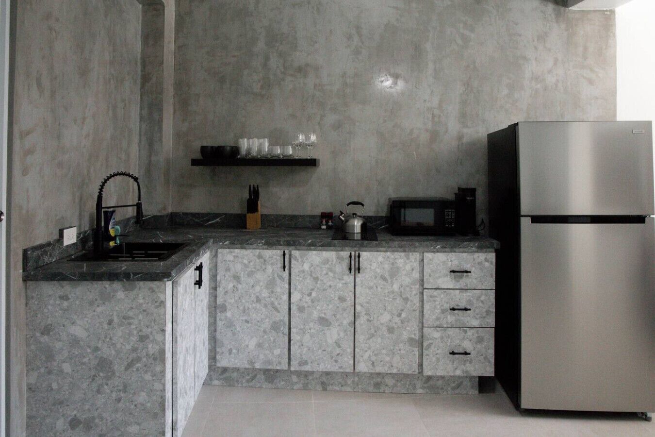 Een keuken met een granieten aanrecht, een roestvrijstalen koelkast en een magnetron.