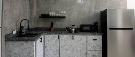 Een keuken met een granieten aanrecht, een roestvrijstalen koelkast en een magnetron.