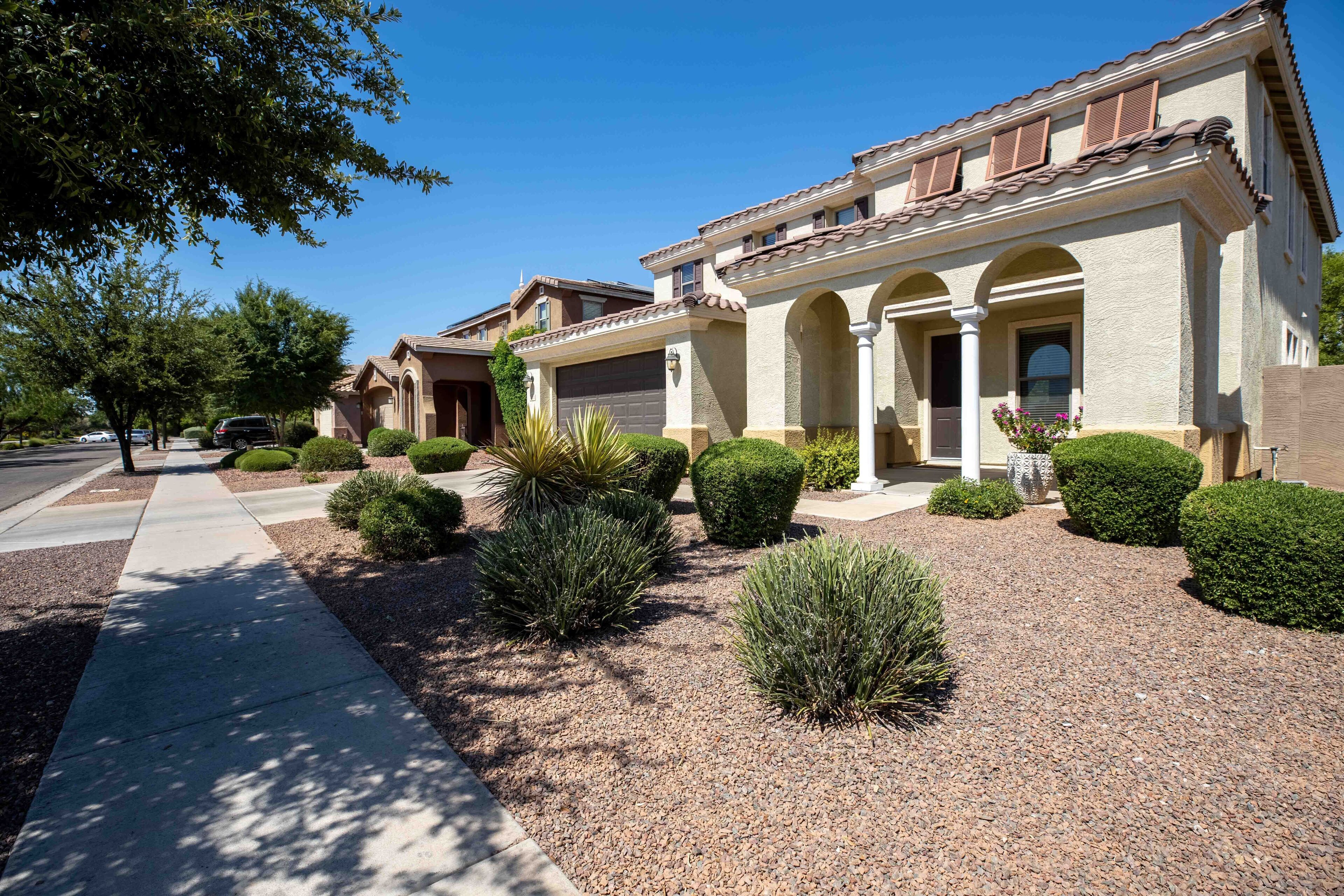 A residential neighborhood with two houses featuring arched doorways and a tiled roof.