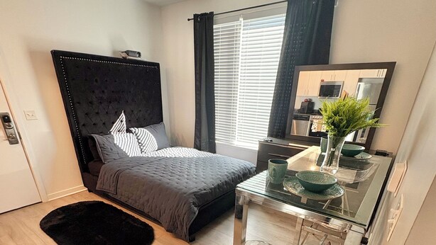 Une chambre moderne avec un grand lit, une table à manger en verre et un petit coin cuisine.