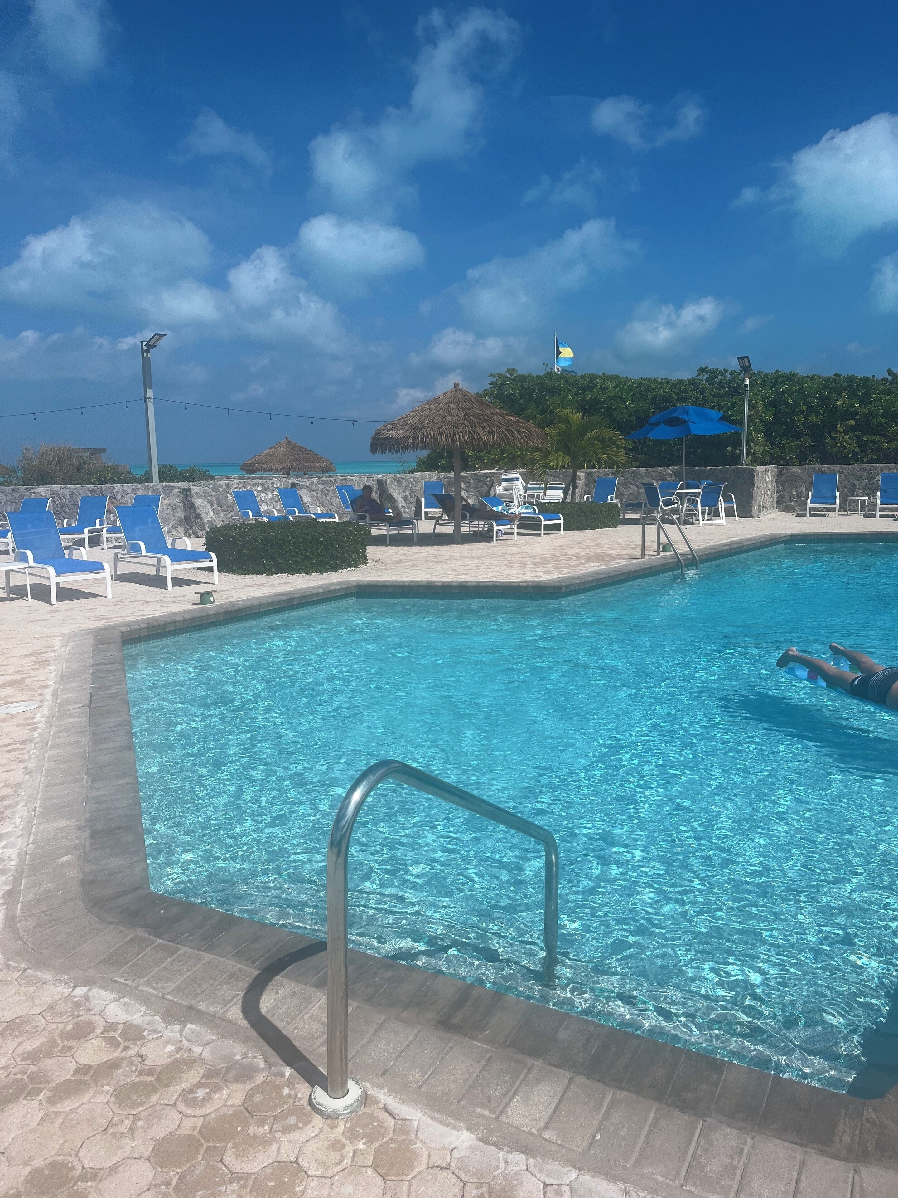 Ein Swimmingpool mit blauem Wasser, umgeben von Liegestühlen und Sonnenschirmen.