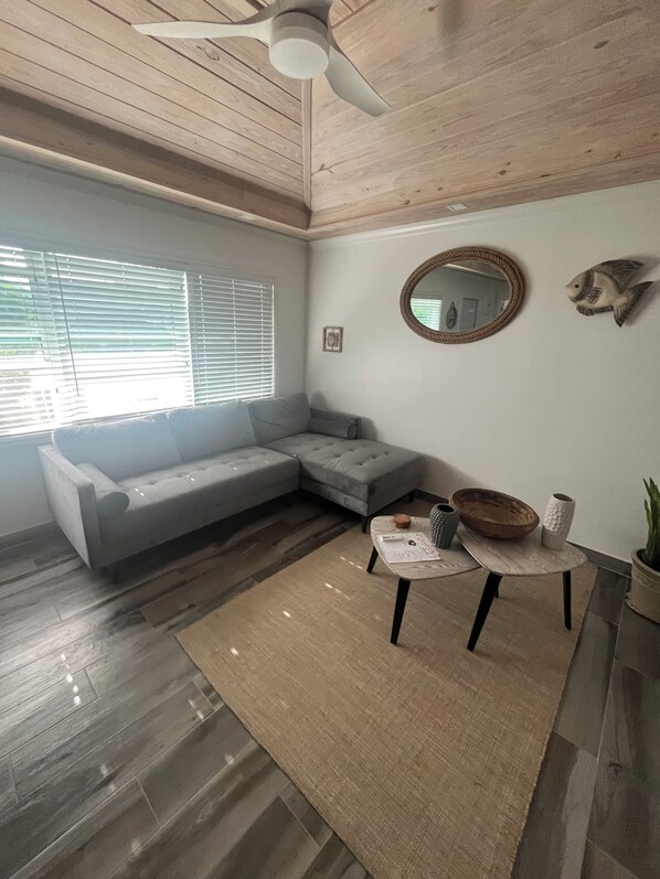 A modern living room with a grey sectional sofa, a round coffee table, and a ceiling fan.