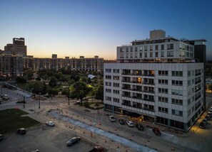 A multi-story hotel with a modern design, featuring a central courtyard and a parking area with several cars.