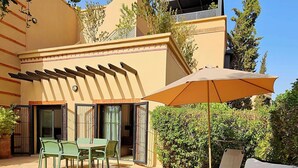 An outdoor patio area with a dining table, chairs, and a sofa.
