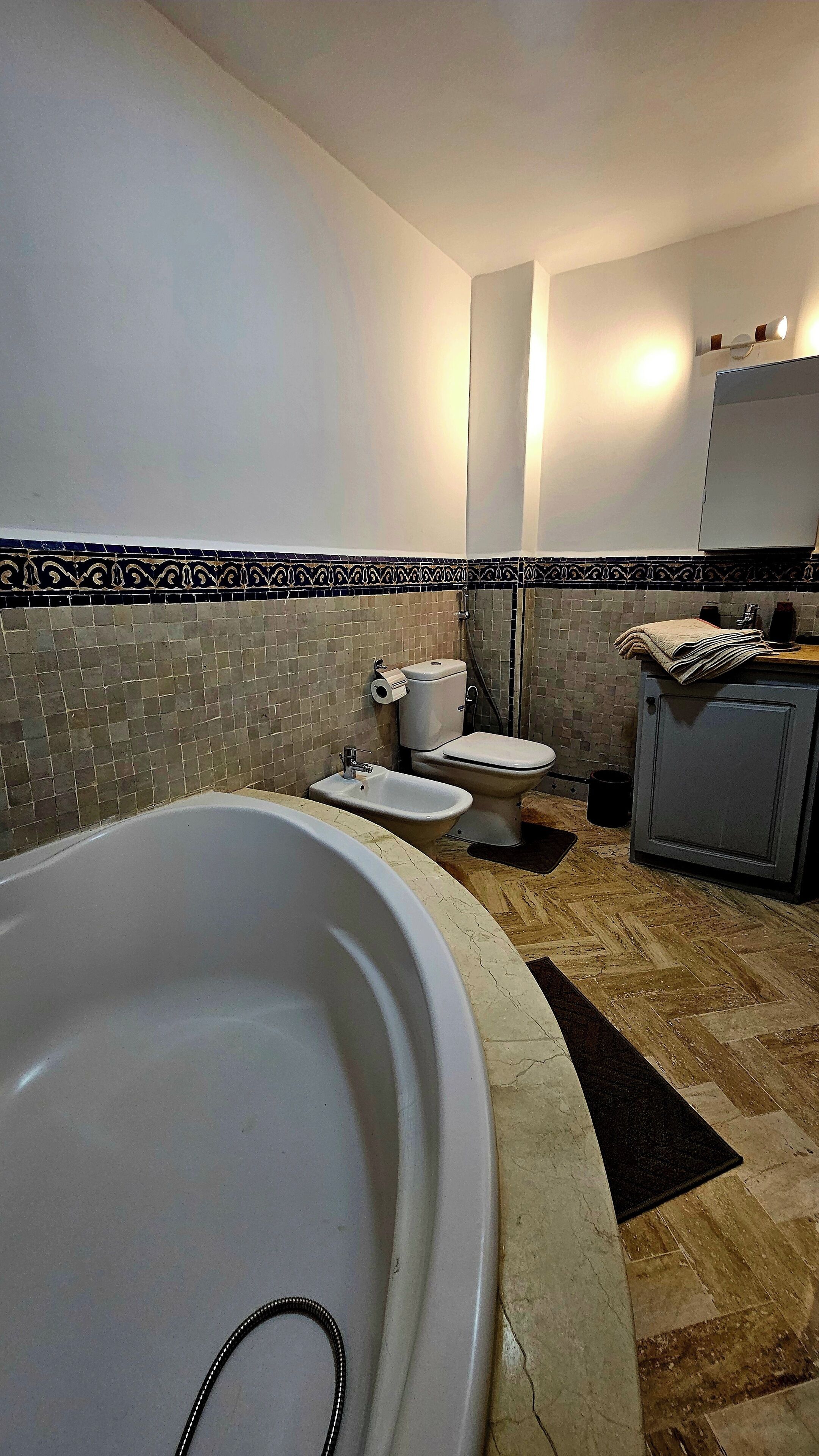 Un baño con bañera, dos inodoros, lavabo y espejo.