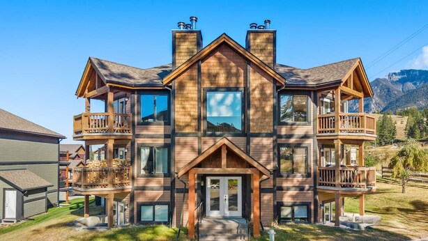 A multi-story wooden building with balconies, large windows, and a central entrance. - Bighorn Manor | Central | Wood Fireplace | Views (Radium Hot Springs)