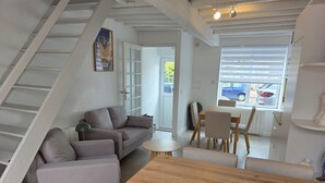 Ein modernes Wohnzimmer mit einer Couch, einem Holztisch und einem Essbereich mit Stühlen.
