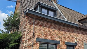 Ein Ziegelhaus mit einem Ziegeldach, einem kleinen Fenster mit Fensterläden und einer Tür.