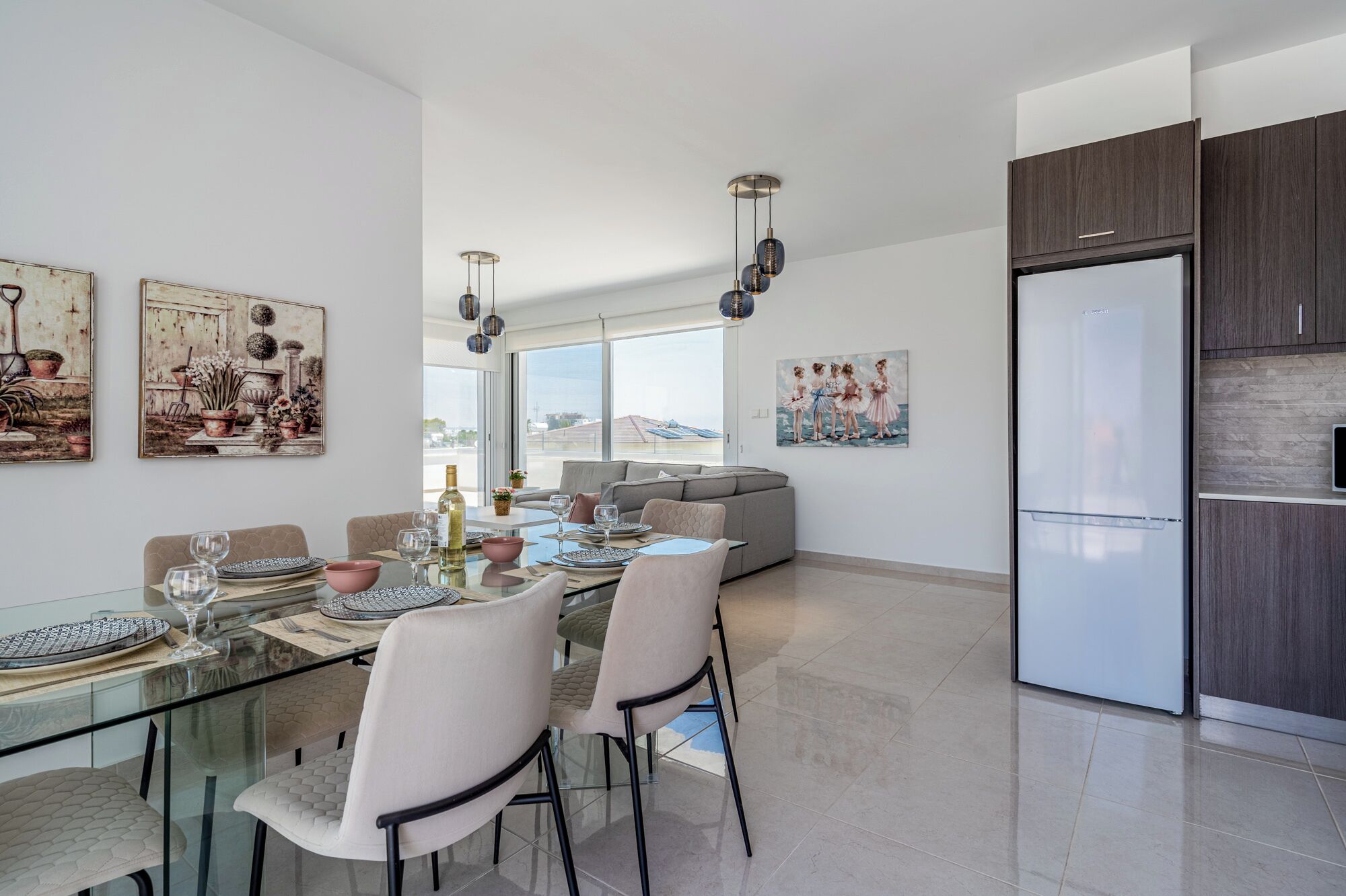 A modern dining area with a glass table, chairs, and a view of the city.