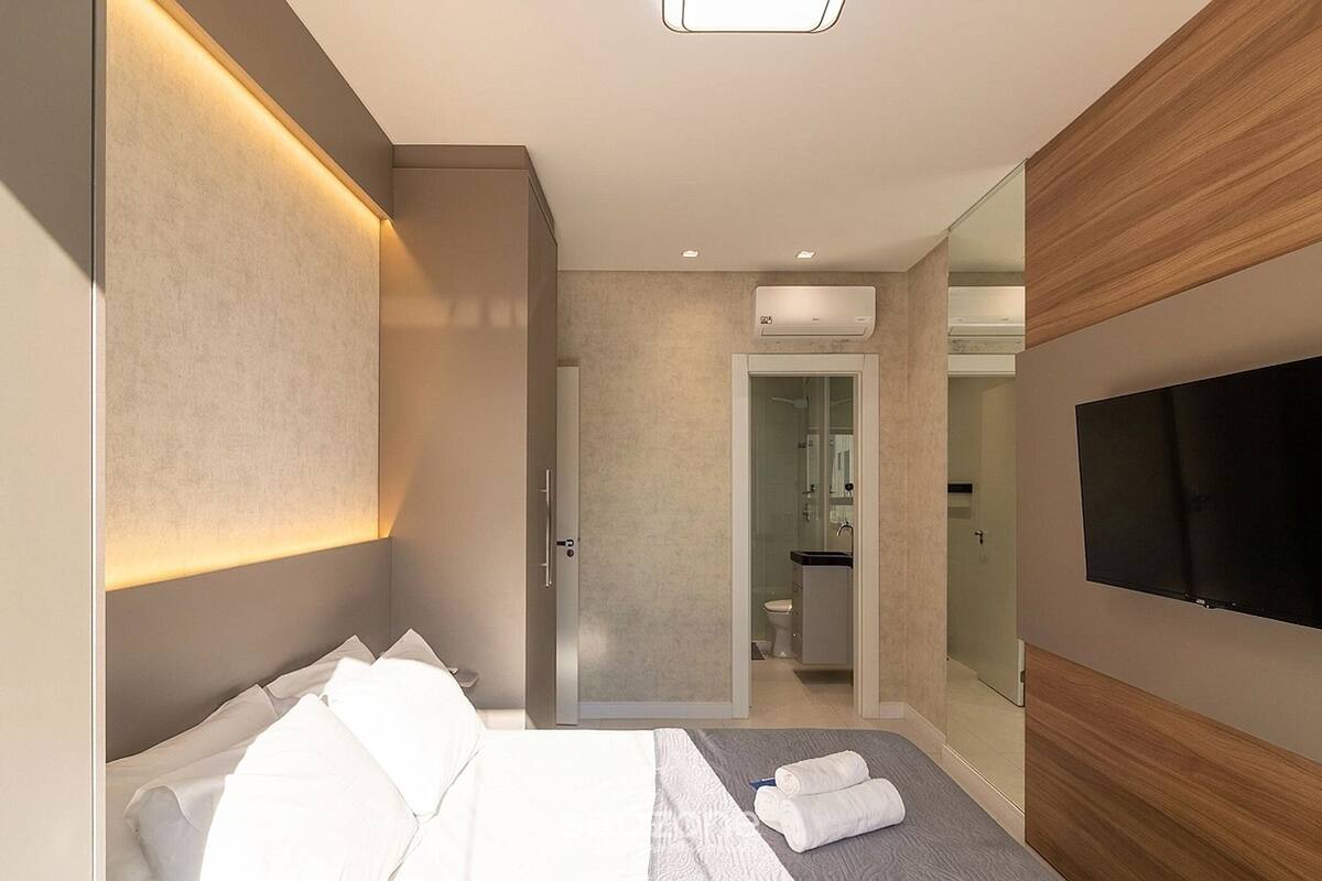 A modern hotel room with a bed, a flat-screen TV, a shower, and a bathroom.