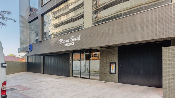 A building with a sign reading 'Miami Beach Residence' and a gated entrance. -  Aptos em prédio a 90 m da praia de Perequê - RIHs (Porto Belo)