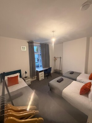 Ein Hotelzimmer mit zwei Betten, einem Schreibtisch, einem Stuhl und einem Fenster mit Vorhängen.