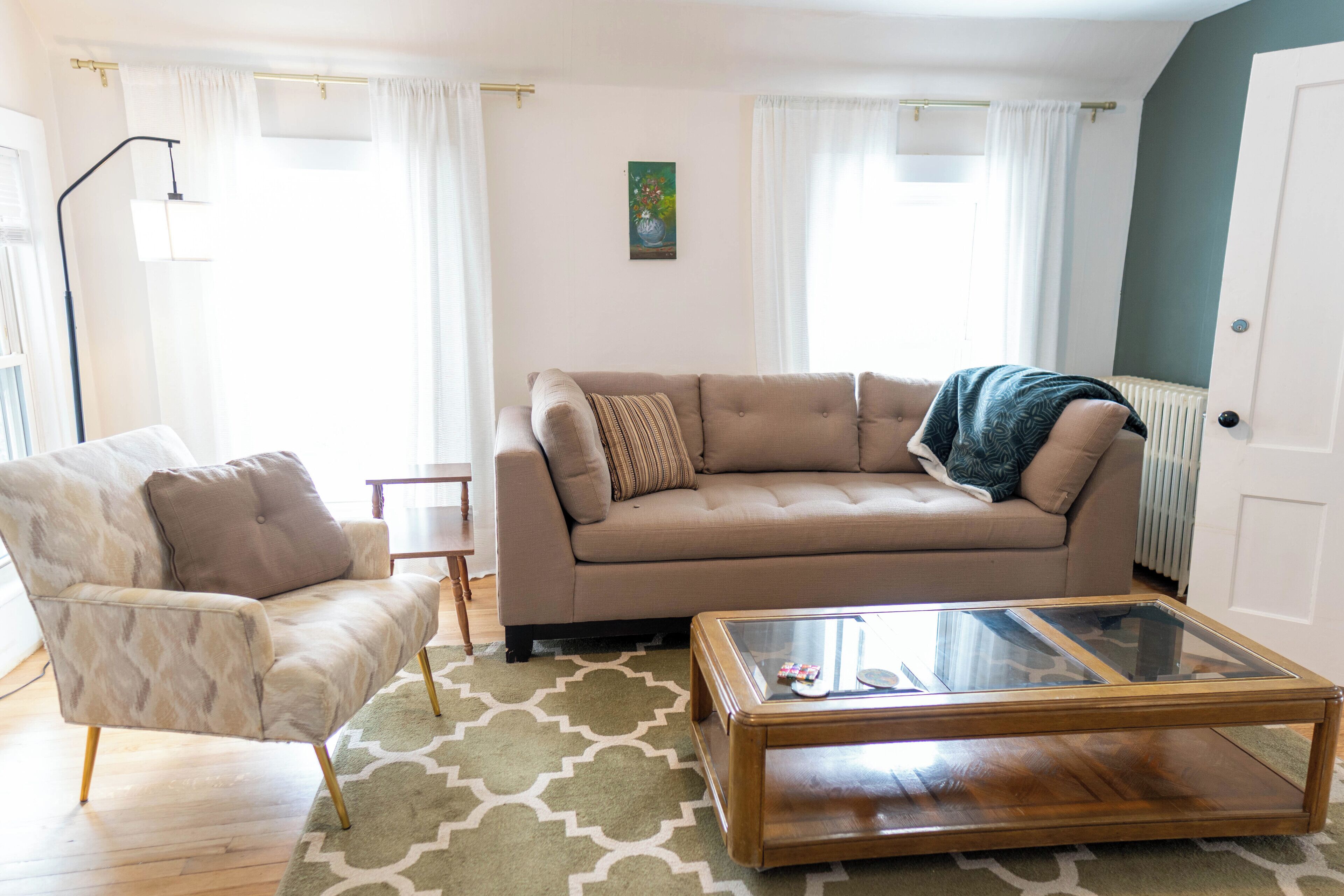 A living room with a beige sofa, a glass coffee table, a patterned rug, and a lamp.