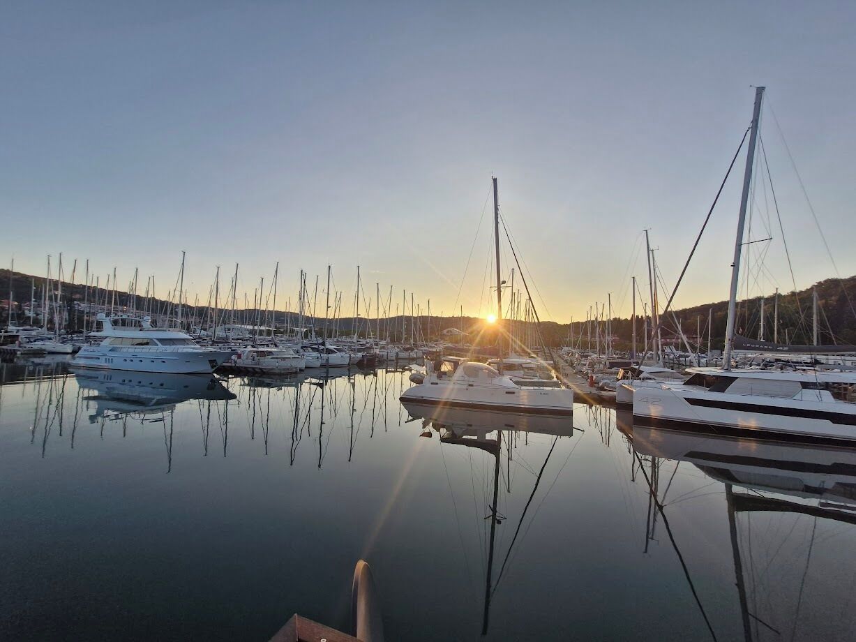Un port de plaisance où sont amarrés de nombreux bateaux, l’eau est calme et le ciel est dégagé.