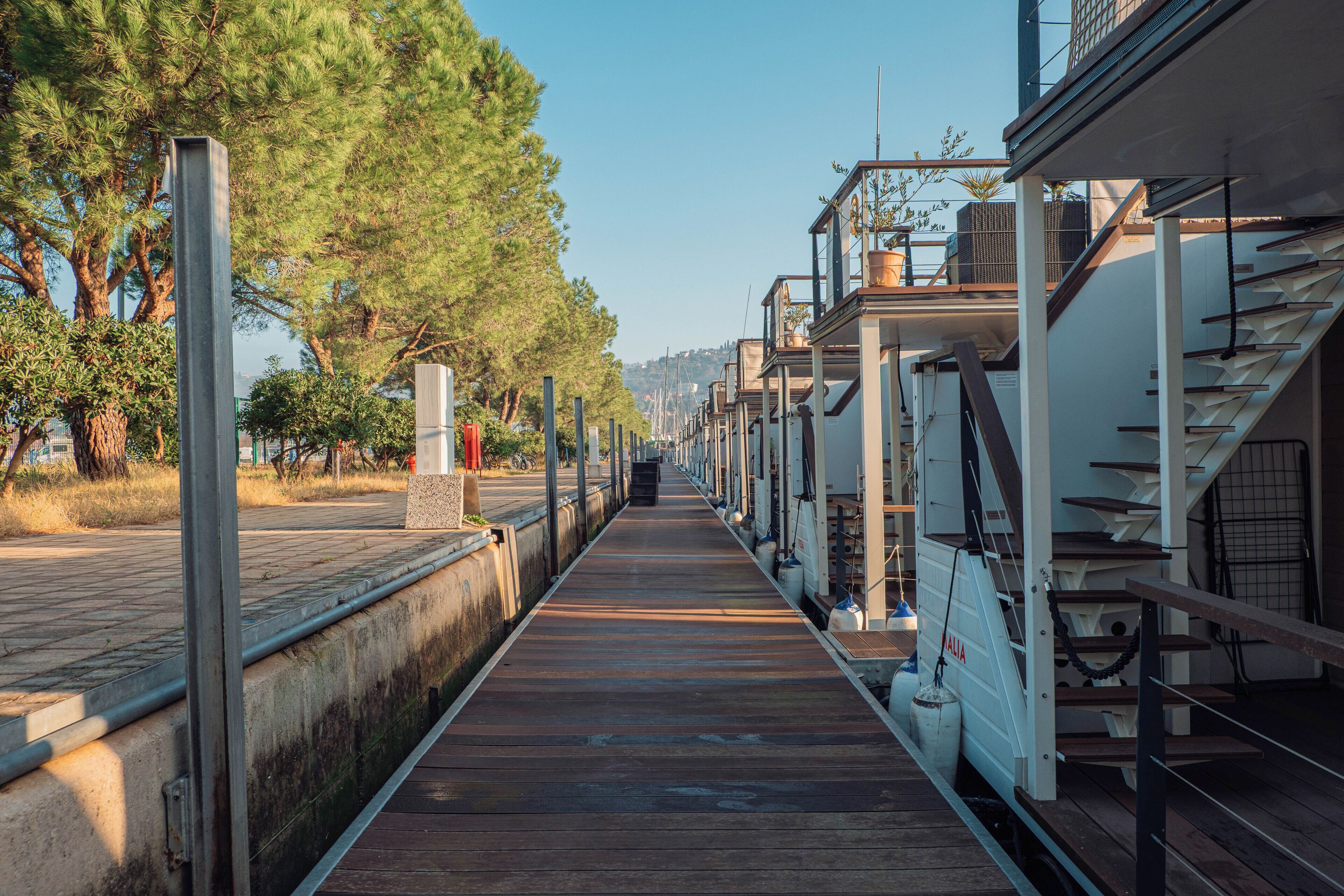 Une promenade en bois menant à un bâtiment à plusieurs étages, agrémenté de plantations extérieures.