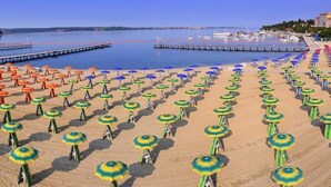 Ein Strand mit Reihen von Sonnenschirmen und einer Pier, die ins Wasser ragt.