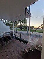 Uma área externa coberta com deck de madeira, uma mesa e cadeiras.
