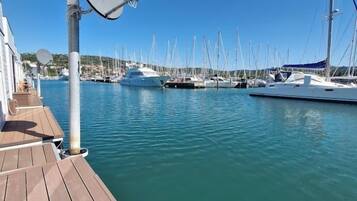 A marina with multiple yachts docked, a wooden deck, and a satellite dish.