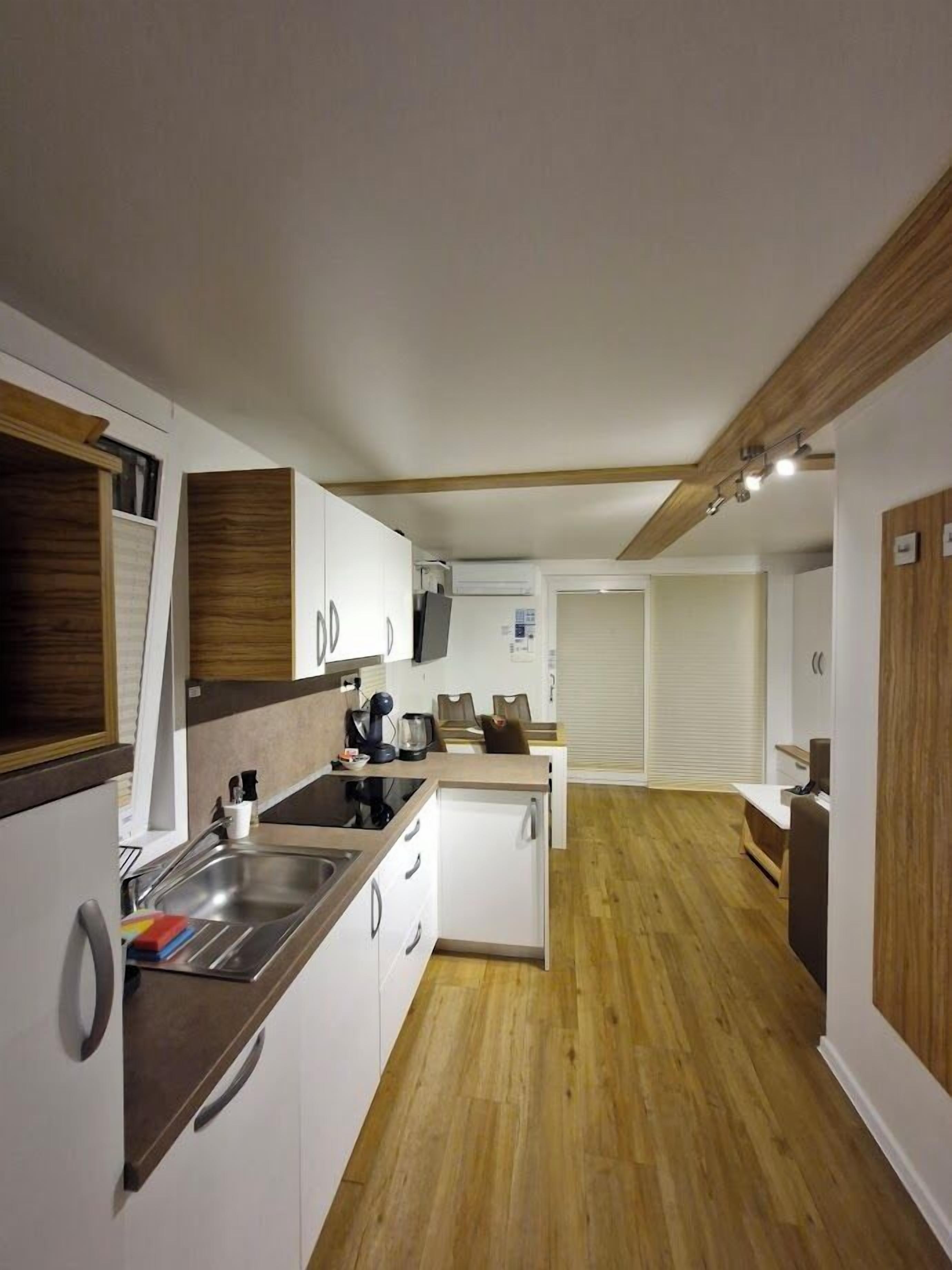 Una cocina compacta con detalles de madera, un horno empotrado y un lavamanos.