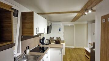 Una cocina compacta con detalles de madera, un horno empotrado y un lavamanos.