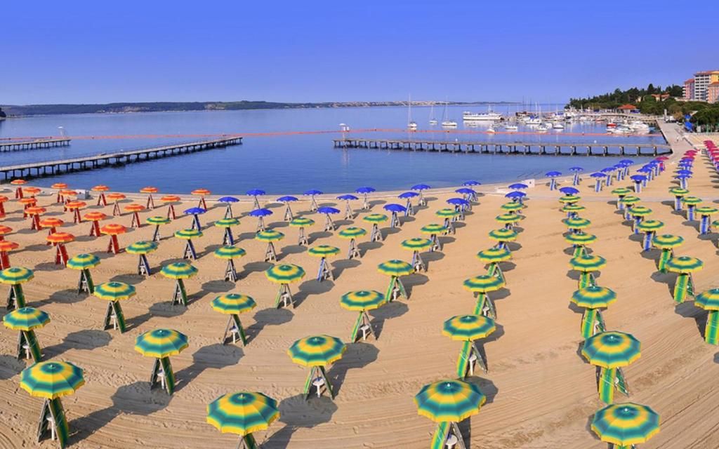 Ein Strand mit Reihen von Sonnenschirmen und einer Pier, die ins Wasser ragt.
