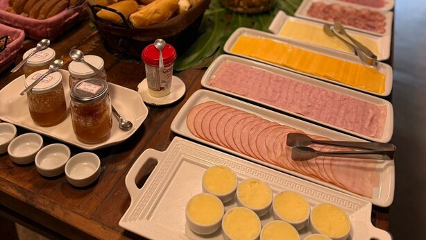A buffet table with various food items including bread, meats, cheeses, and condiments. - Pousada Brisa Do Vale (Barra do Piraí)