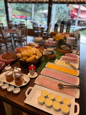A buffet table with various food items including bread, meats, cheeses, and condiments. - Pousada Brisa Do Vale (Barra do Piraí)