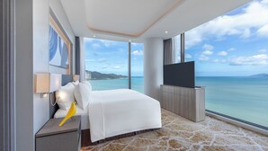 Una habitación de hotel moderna con una cama grande, televisión de pantalla plana y vista al mar.