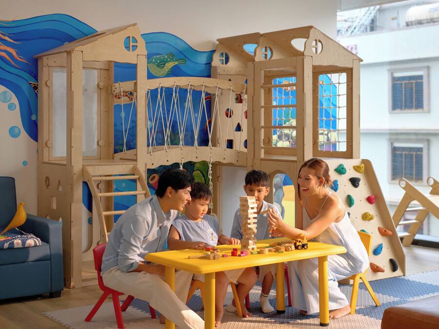 A play area with a wooden playhouse, a table with wooden blocks, and a blue couch.