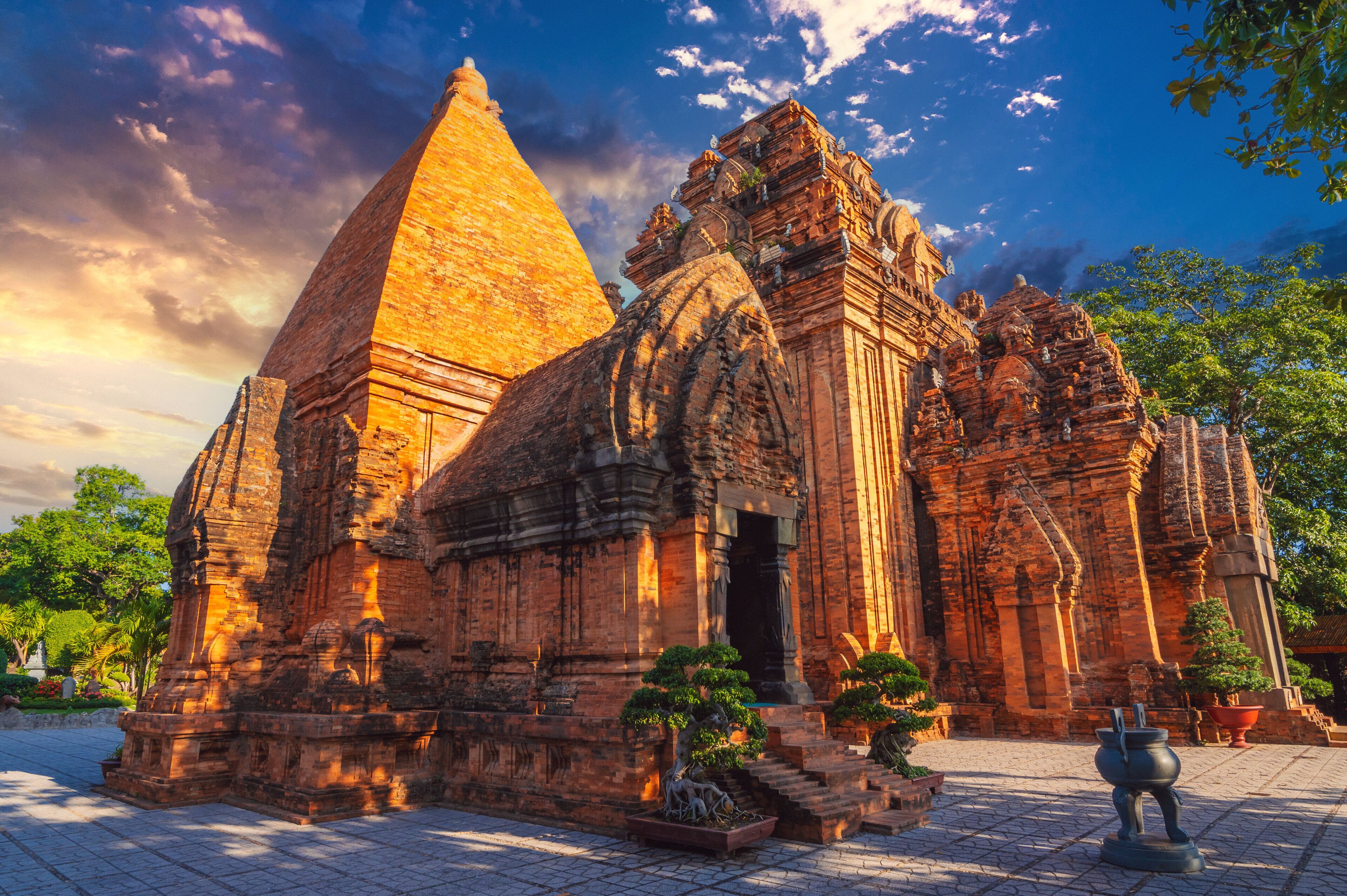 A temple with a large pyramid-like structure, intricate carvings, and a paved entrance area.