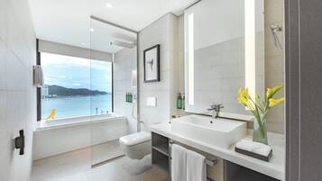 Une salle de bain moderne avec une grande fenêtre, une baignoire, un lavabo et un miroir.