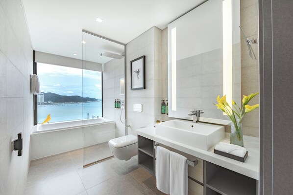 A modern bathroom with a large window, a bathtub, a sink, and a mirror.