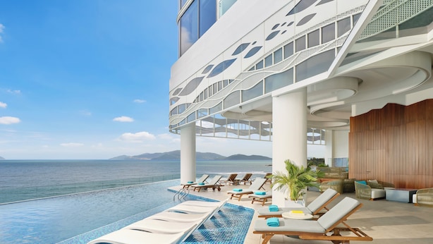 Zona de piscina con sillones de descanso, vista al mar y diseño arquitectónico moderno.