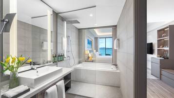 Un baño moderno con un espejo grande, lavamanos dobles, una bañera y una ducha.